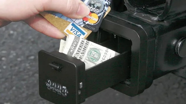 A person using a HitchSafe hitch lockbox to stash cash and credit cards