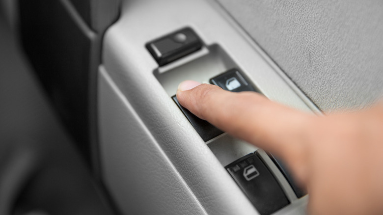 Finger pressing down on car power window button