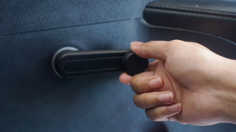 Hand operating a manual car window crank.