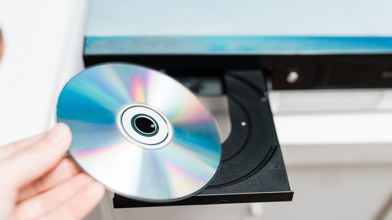 Person inserting a CD in the disc tray of a disc player