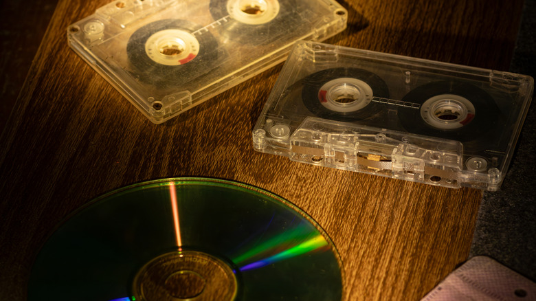 Two transparent audio cassettes placed alongside a CD on a wooden table