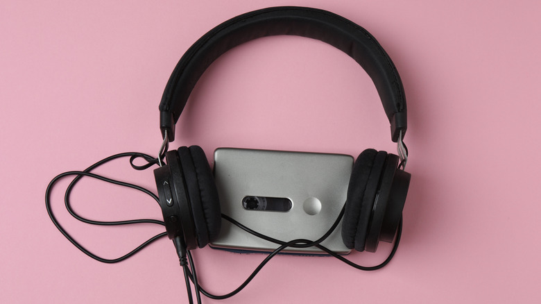 A portable cassette player with headphones connected to it on pink background
