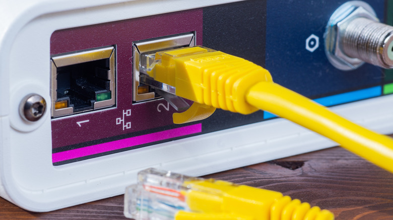 Yellow ethernet cable connected to a network router port close up.