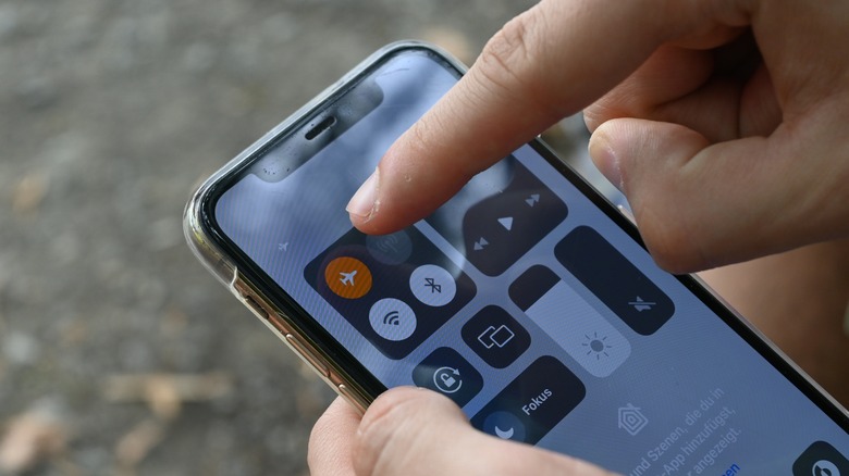 Close up of a person tapping the airplane mode icon on an iPhone