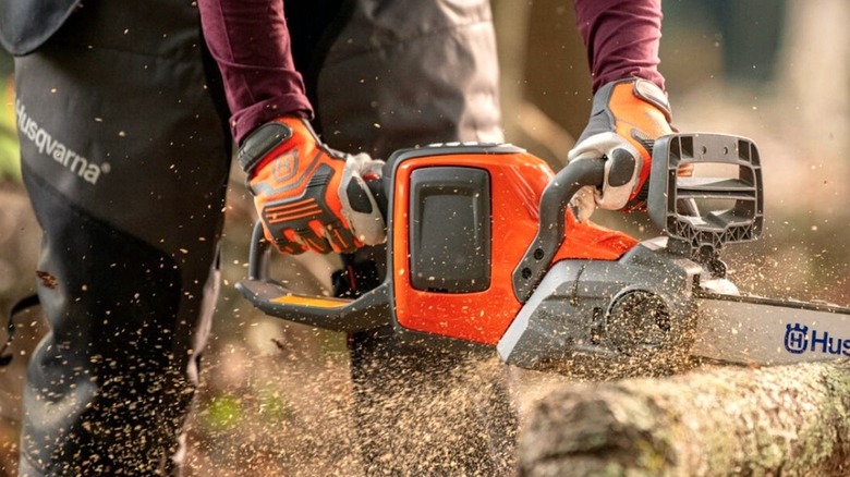 Person cutting wood with a Husqvarna chainsaw