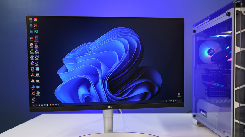 An LG monitor displays a Windows 11 desktop on a desk next to a gaming PC