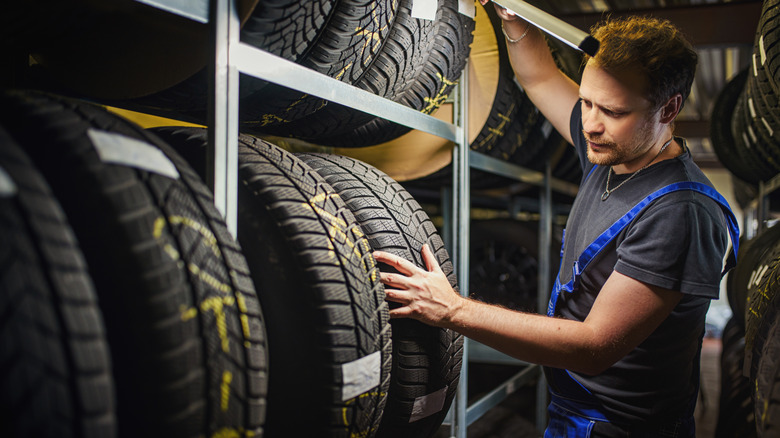 A worker inspecting tires on a rack.