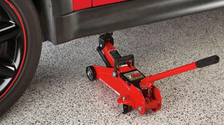A Pittsburgh 2 Ton Compact Trolley Jack lifting up a car.