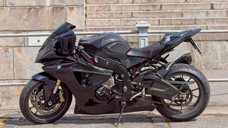 A BMW S1000R, finished in matte black, parked at the side of a city street.