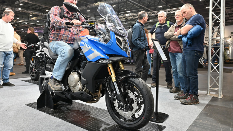 A CFMoto 650MT bike finished here in blue being looked at by a crowd of onlookers at the MCN London motor show.