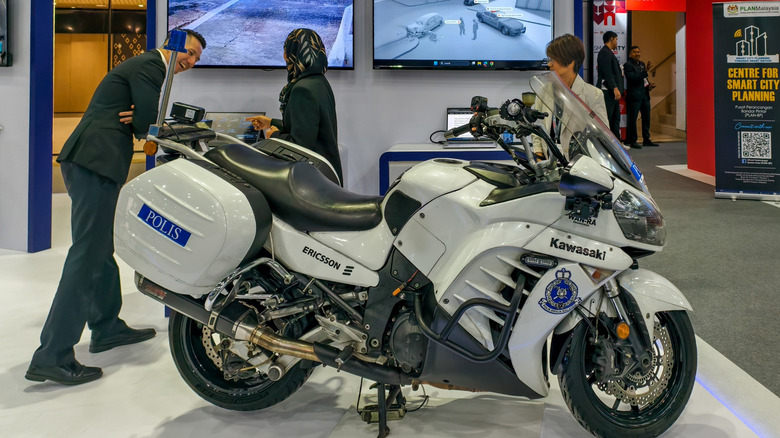 A white Kawasaki Concours 14, known officially as the Kawasaki GTR1400, parked indoors on a podium.