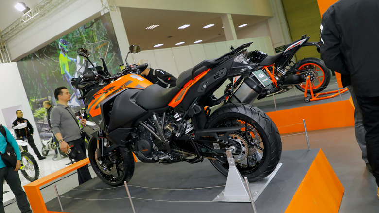 A black and orange KTM 1290 Super Adventure S off road motorbike parked inside a store, on display for buyers.