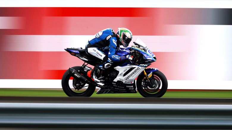 A rider in full kit and helmet riding a Yamaha YZF-R6 finished in white on a track at speed.