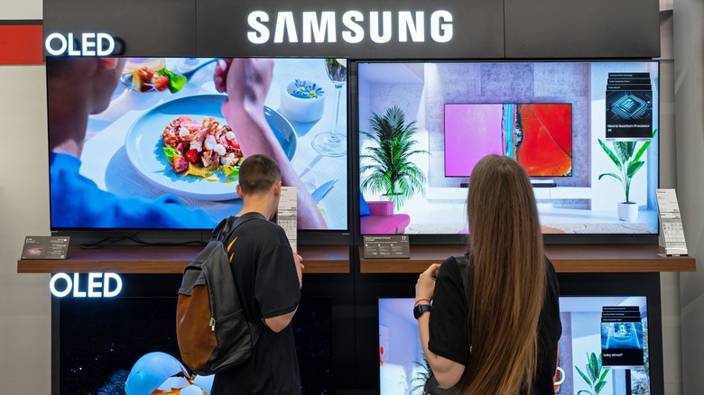 Two people looking at Samsung OLED TVs on display