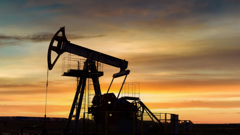 Silhouette of a land-based oil pump in operation during sunset
