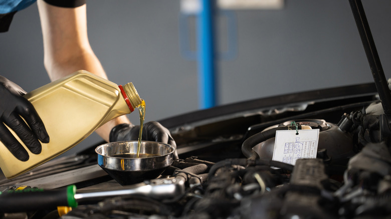 Close-up side-view of mechanic changine a car's engine oil