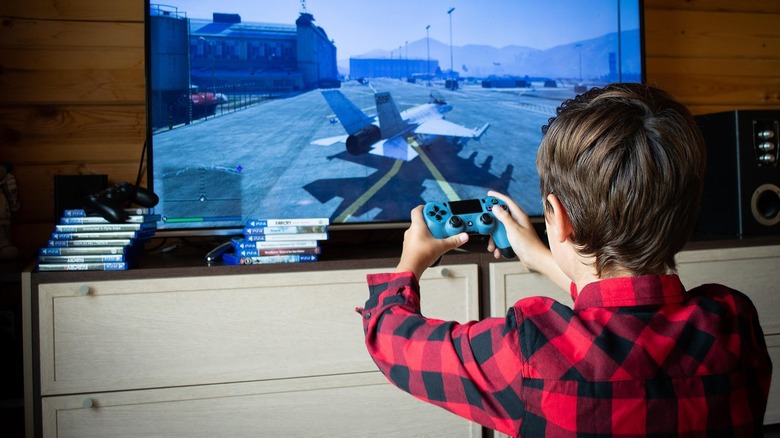 A person playing Grand Theft Auto 5 on a PlayStation and holding a Dualshock 4 controller.