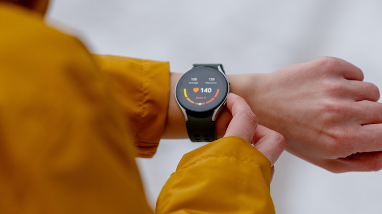 Person using side buttons on a smartwatch fitness tracker on their wrist.