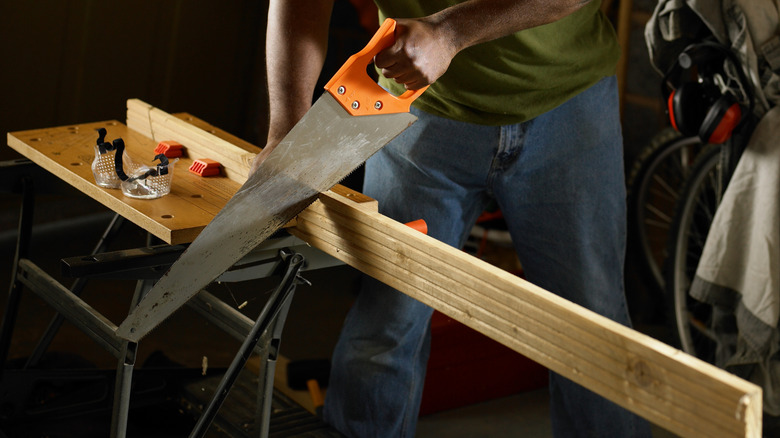 Person sawing wood on a sawhorse