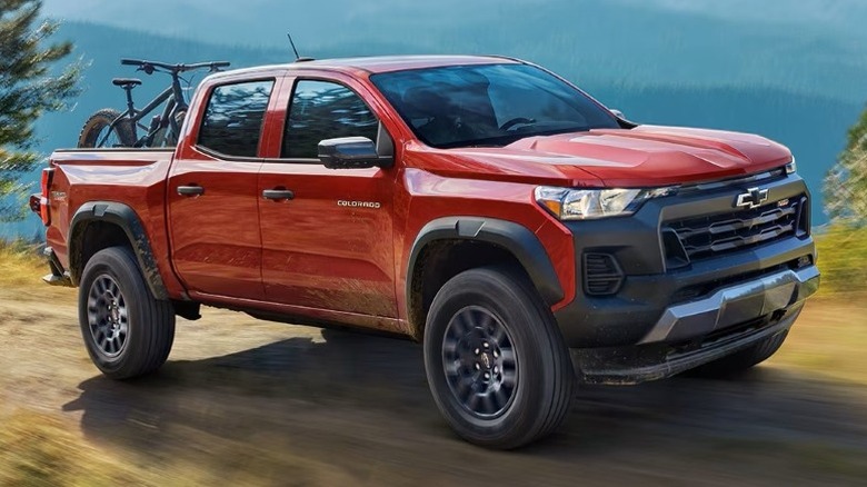 Chevrolet Colorado driving on a dirt road with mountains in the background