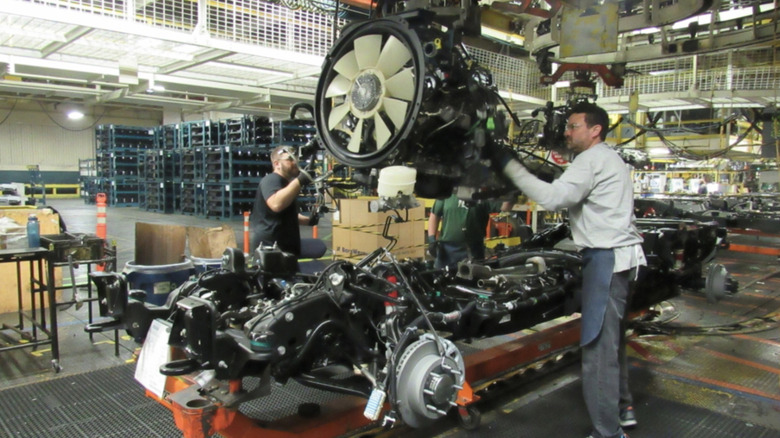 Assemblers installing 6.6-liter Duramax engine in new truck chassis