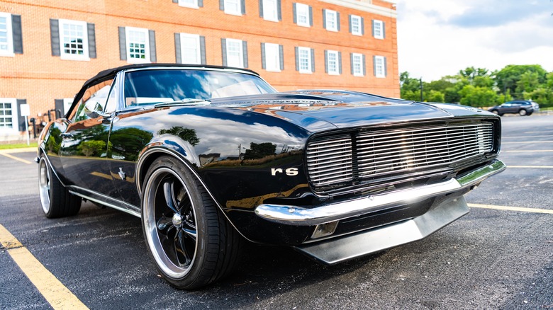 low front right view of black 1967 Chevrolet Camaro SS in a parking lot in front of brick building