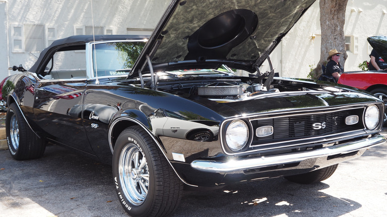 A black 1967 Chevy Camaro SS with its hood up, showing its engine