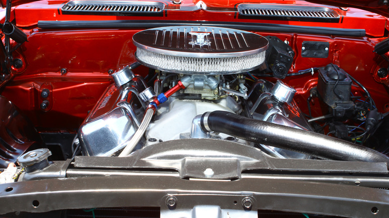 An orange Chevy Camaro engine bay, featuring a big block 396 powerplant with chrome valve covers and air cleaner