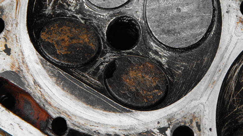 A close-up of a worn cylinder head with one heavily burnt exhaust valve