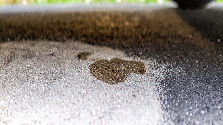 A close-up of an oil stain under a car parked on a concrete surface