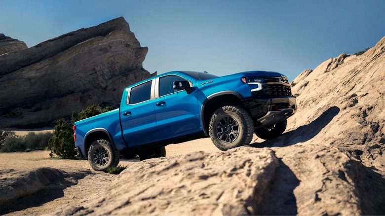 A blue 2024 Chevy Silverado climbs a rocky hill