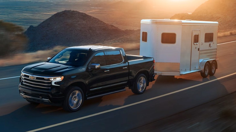 Lakeshore Blue Metallic Chevy Silverado 1500 High Country towing a horse trailer on a paved road