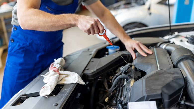 Mechanic checking car's oil level with a dipstick