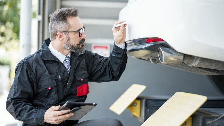 Man examining the trunk lid of car