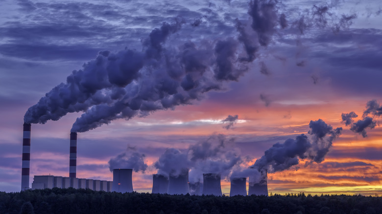 A coal powered power plant with smoke visible from the cooling towers