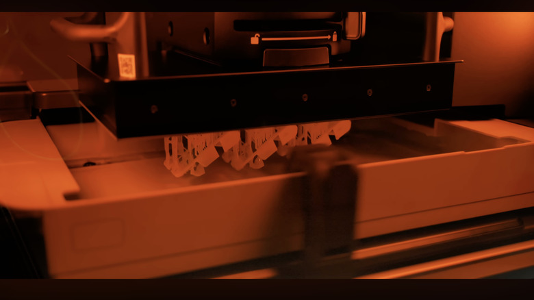A 3D printer prints an object using resin under warm lighting