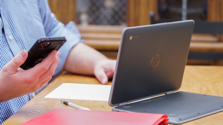 Chromebook on desk, Pixel phone in hand