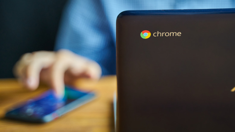 Person using a Chromebook and smartphone