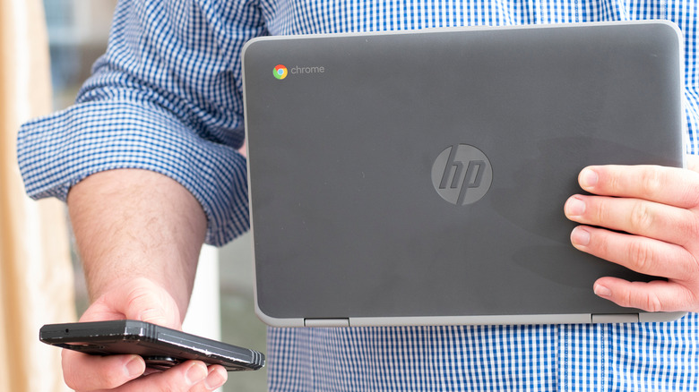 Man holding an HP Chromebook and a phone