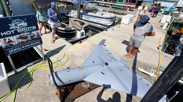 People gathered around a LUCAS drone on a dock beside several fishing boats