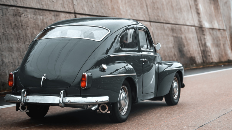 Classic Volvo PV544 driving on highway, rear-right three-quarter view