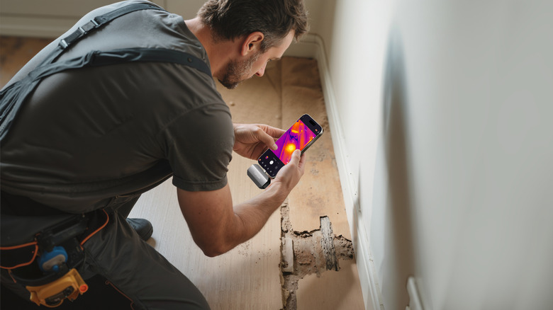 A worker using a phone with the TOPDON TC002C Duo on a floor.