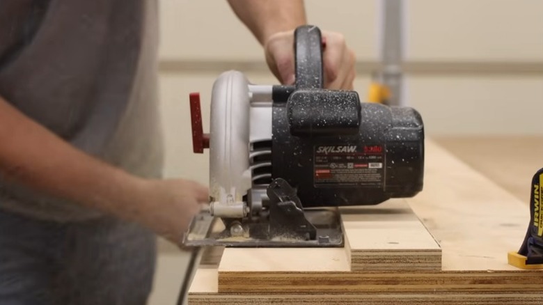 Person cutting wood aided by a circular saw guide jig