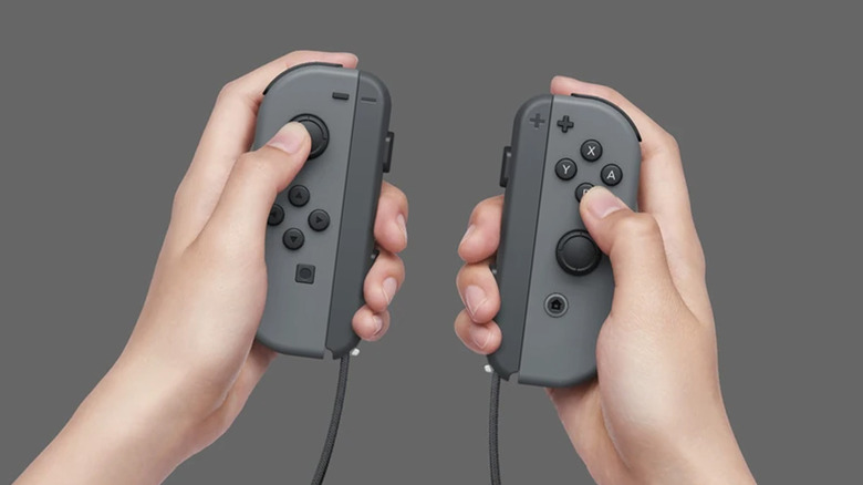 A pair of hands holding a Nintendo Switch controller over a white background