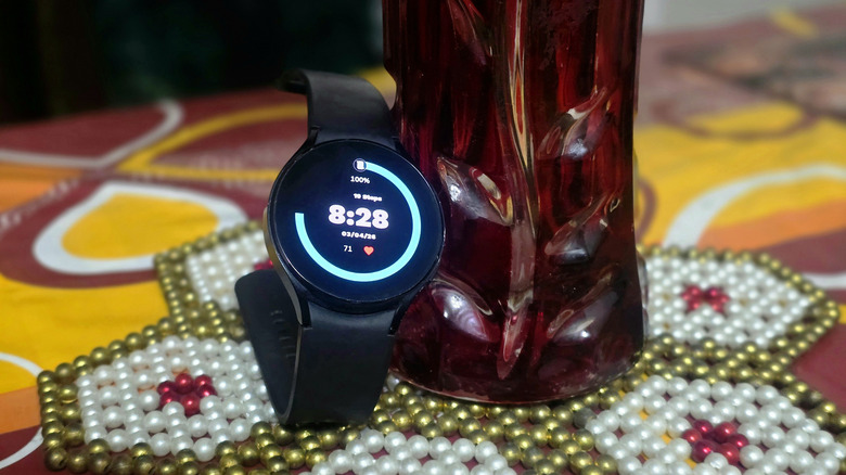 A Samsung Galaxy Watch4 with a digital clock in AOD mode
