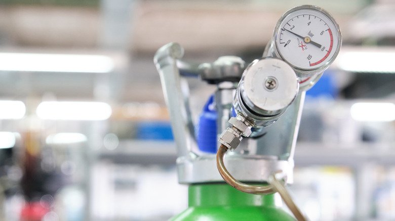 Close-up of a gas cylinder with pressure gauge on a green tank in a laboratory