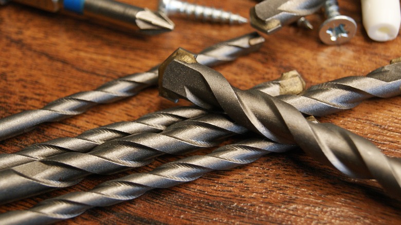 Close-up of drill bits, screws, and screwdriver bits on a table