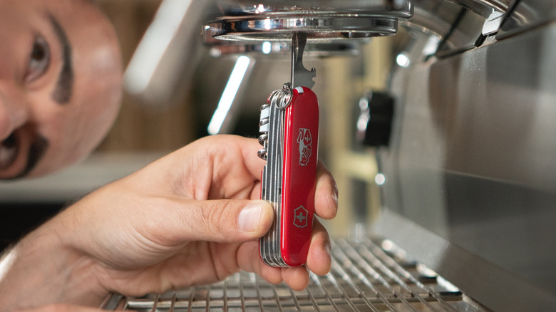 A barista uses a Victorinox x La Marzocco barista tool to adjust an expresso machine