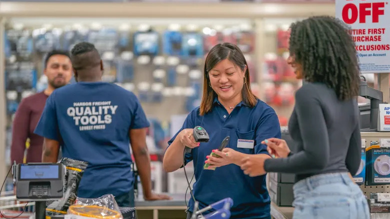 An African-American women being checked out at a Harbor Freight store by a female employee in a blue shirt