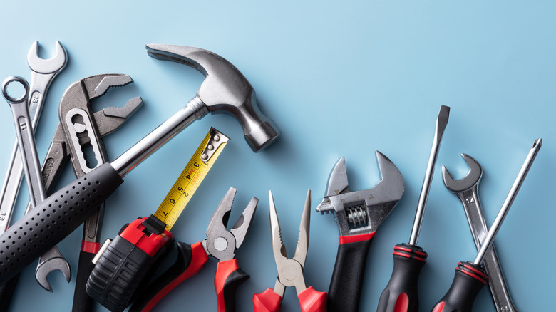 A variety of hand tools laying on blue surface